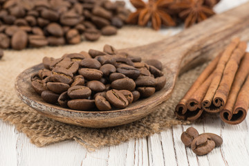 Coffee beans in a wooden spoon on old wooden table.