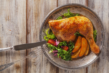 Baked chicken leg, served with roasted potatoes and vegetables.