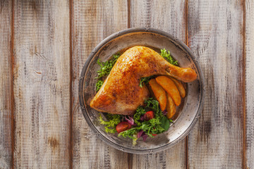 Baked chicken leg, served with roasted potatoes and vegetables.