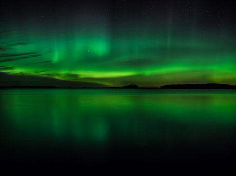 Northern lights dancing over calm lake in Sweden