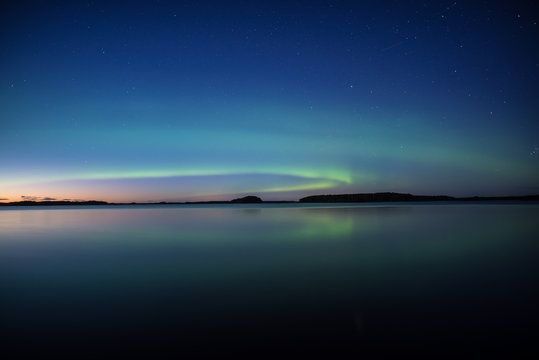 Northern lights dancing over calm lake in Sweden