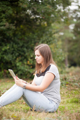 Young teenage girl using tablet outdoor; looking concentrated an