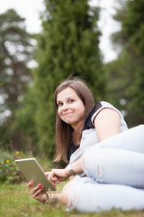 Young teenage girl using tablet outdoor; looking concentrated and happy (color toned image)