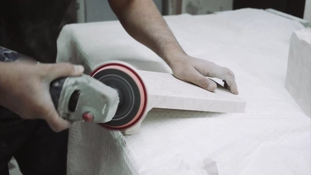 Worker polishes marble plate with tools