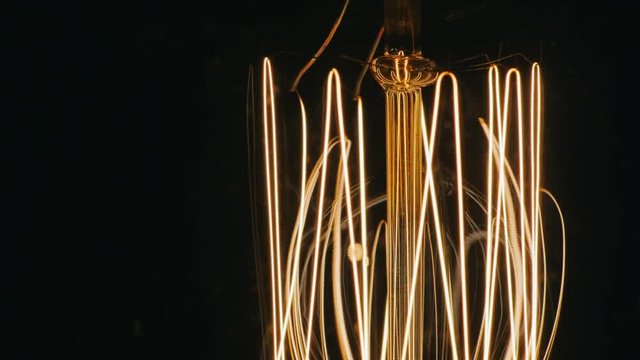 Close-up of spiral light bulb. Slowly illuminates. On a black background