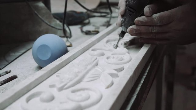 Engineer engraver working with tools on a marble ornament plate, close up