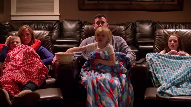 A Family Watching A Movie In A Home Theater With Blankets And Popcorn