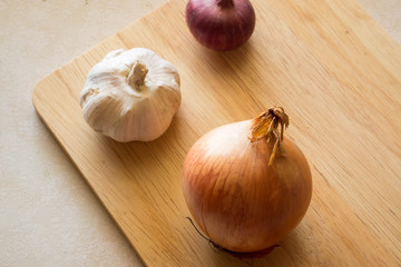 white garlic, big onion and red shallot on chopping wooden board background
