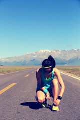 Fototapeta premium young fitness woman runner tying shoelace on road