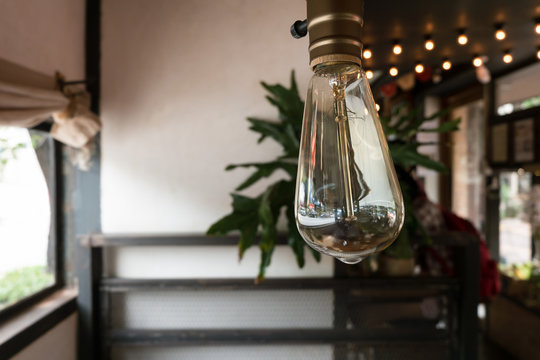 Edison style light bulb with its reflection in cafe.