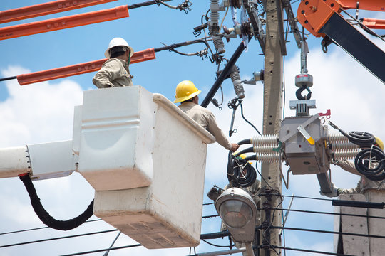 men working on a transformer on a electricity power pole in Thailand