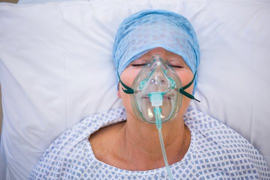Patient wearing oxygen mask lying on hospital bed