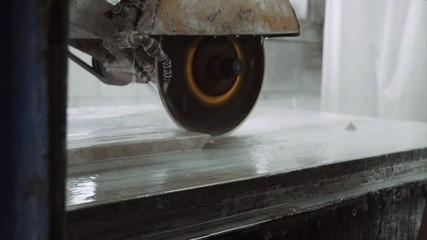 Saw machine makes a cross-section on the marble stone plate , close up