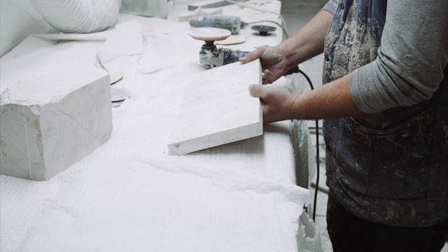 Worker polishes the piece of marble stone with tools