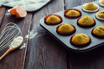 Baked matcha tea cupcakes and muffins in a tray on a rustic dark wooden background