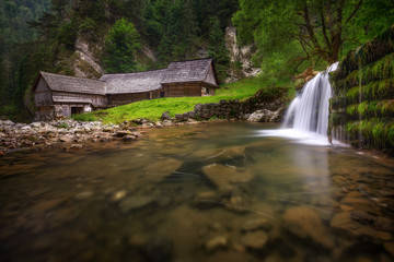 Beautiful hidden wooden water mill at National Nature Reserve Kvacianska dolina valley. Amazing calm water motion during summer day in Slovak village, Slovak republic.