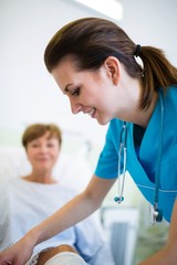 Fototapeta premium Nurse bandaging leg of patient 