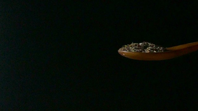 Wooden spoon sprinkling cumin seeds