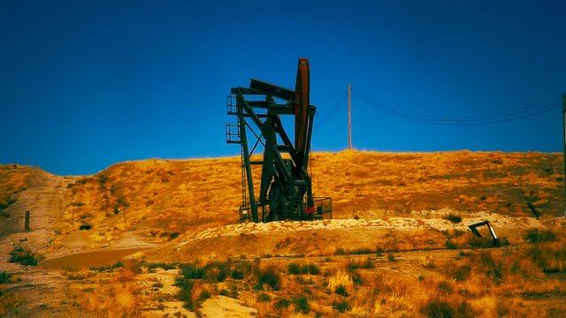 A oil rig drills for oil on a hillside.