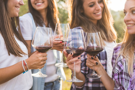 Smiling Girls Toasting with Red Wine Outdoors
