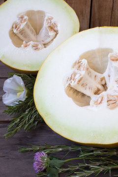 Sliced melon with a rosemary on rustic wooden background, close