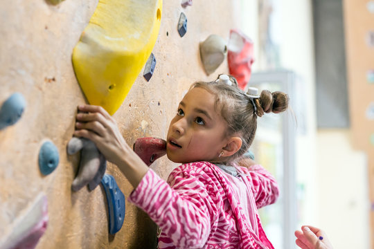Junior Climber hanging on holds on climbing wall