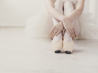 Ballerina puts on pointe ballet shoes, graceful legs