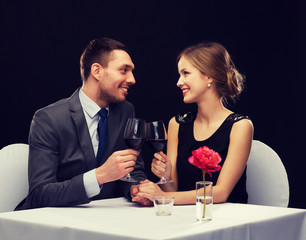 young couple with glasses of wine at restaurant