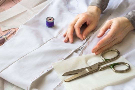 Seamstress is stiching  zipper to a white material with blue thread. Style and design development and creating garment, clothes sew and repair service, seamstress at work concept 