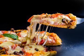 cut off a slice of pizza. melted cheese stretches from the piece - 122241049
