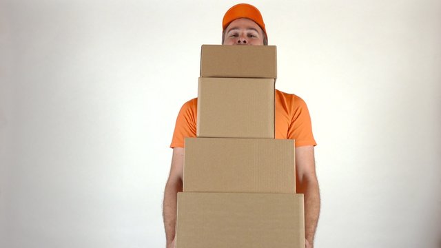 Courier in orange uniform delivering a pile of parcels. Light grey backround