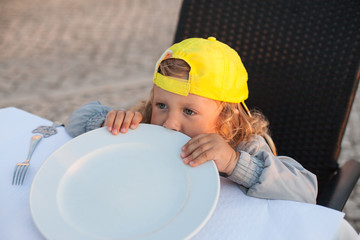 Little kid with curly hair waiting meal at outdoor restaurant   © Tatiana Murr