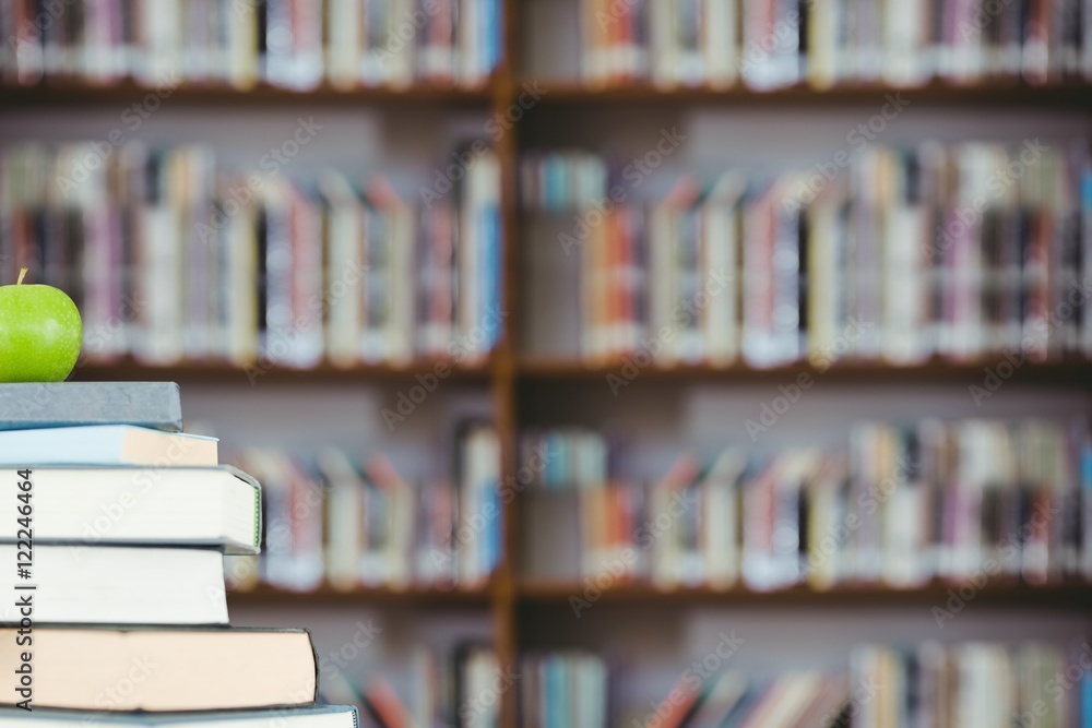 Poster stack of books and green apple with library background
