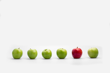 Row of fresh green apples with a single red one