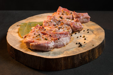 Raw pork ribs with spices, salt and rosemary on dark wooden background