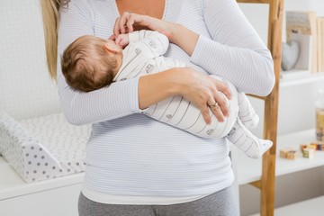 Mid-section of mother holding her baby boy