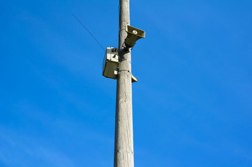 Loudspeaker of siren / alarm. Audio device for making loud noise and producing warning sound that warns and alerts public during danger and emergency. Bright blue sky as copy space