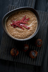 Chestnut cream-soup with meat topping, dark wooden background
