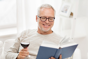 happy senior man drinking wine and reading book