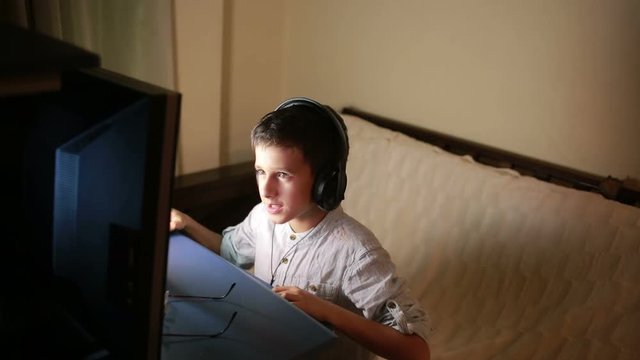 Teen boy plays games on the computer at night. Online Games