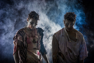 Two male zombies standing on black smoky background, head and shoulder shot