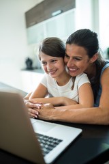 Mother and daughter using laptop and tablet