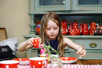 Cute little girl preparing tea in teapot