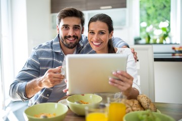 Fototapeta na wymiar Couple using digital tablet while having breakfast at home