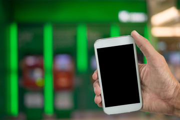 holding mobile phone with blur ATM background