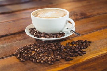 Cappuccino with coffee beans on table