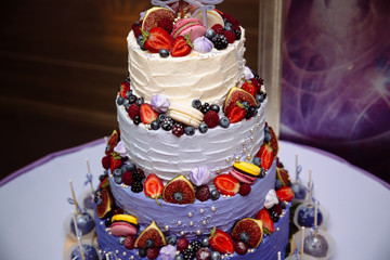Obraz na płótnie Canvas Sweet multilevel wedding cake decorated with fruits. Blueberries, strawberries, raspberries. Candy bar on bottom