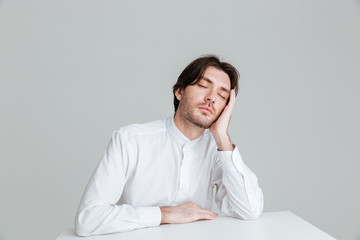 Hadsome young man in white shirt sleeping at the desk