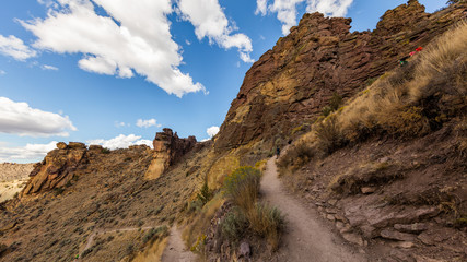 The path among the rocks. The sheer rock walls. Beautiful landscape of yellow sharp cliffs. Dry yellow grass grows on the slopes of the mountains. Smith Rock state park, Oregon