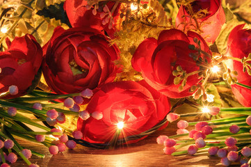 Naklejka premium Artificial flowers lit with Christmas lights. Artificial roses, beautiful composition.